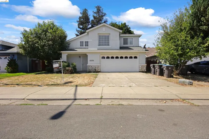 Two-story stucco exterior with an attached two-car garage, stone façade accents, and a covered entry
