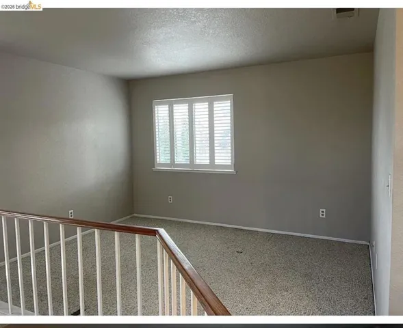 Upper-level area featuring a window with white plantation shutters, neutral-toned walls, and carpet flooring