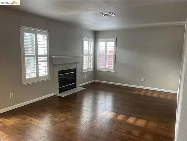 Living area featuring wood-finish flooring and a fireplace with a tiled surround