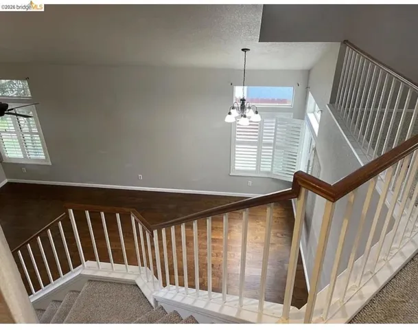 Two-story interior with wood-finish flooring, white plantation shutters, and a chandelier lighting fixture