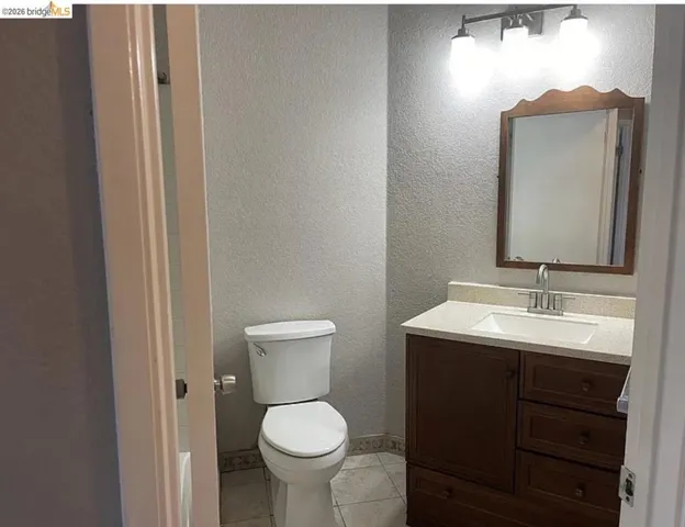 Bathroom featuring a wood-finish vanity with an integrated sink, a light-toned countertop, and a wood-frame mirror