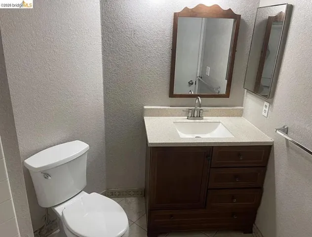 Bathroom featuring a dark wood-finish vanity with an integrated sink, light-toned countertop, and chrome faucet