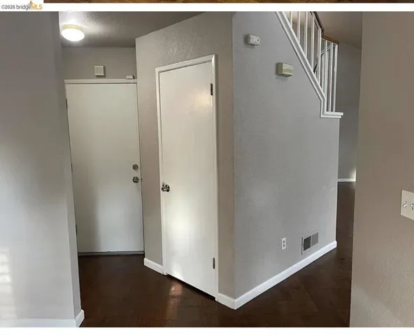 Entryway featuring wood-finish flooring, light gray wall paint, white baseboards, and a white staircase with a contrasting handrail