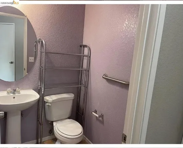 Bathroom featuring a pedestal sink, white toilet, and an oval wall mirror