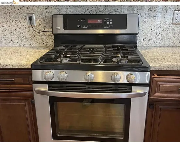Stainless steel range with a gas cooktop, integrated oven, and overhead digital display