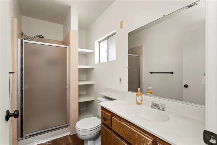 Original bathroom with shower and new wood-vinyl flooring.