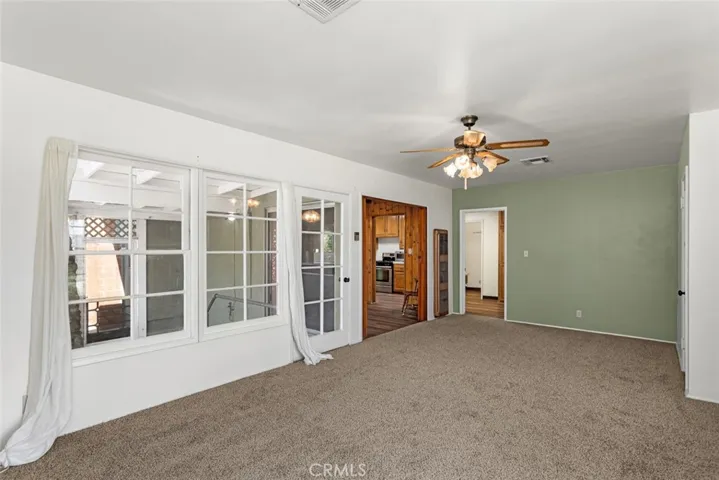 Living room with vintage ceiling fan, new carpet, and access to the lattice-enclosed covered patio.