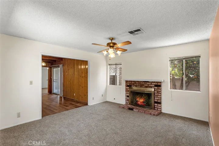 Family room with new carpet, brick fireplace and vintage ceiling fan.