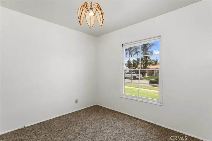 Front bedroom with view of the neighborhood, new carpet and vintage light fixture.