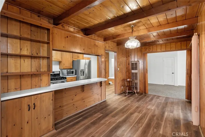 Wood paneled dining room with built-in cabinet and shelving, vintage Tiffany-style light fixture, breakfast bar and new wood-vinyl flooring.