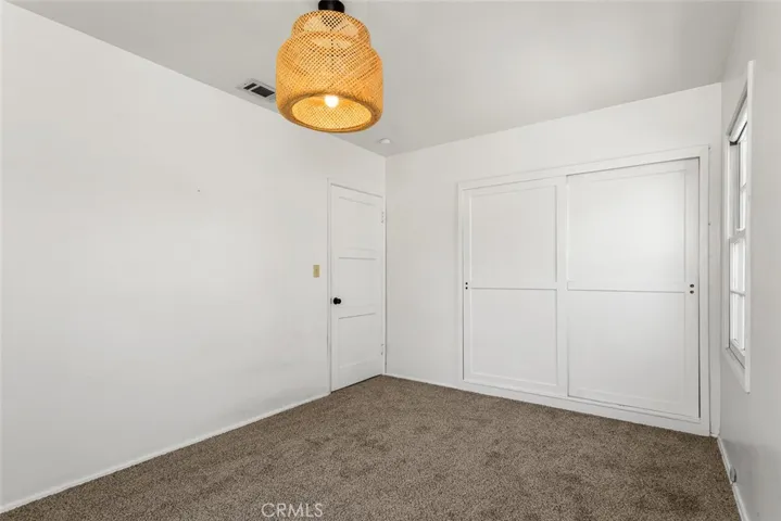 Front bedroom with sliding closet doors, vintage light fixture and new carpet.