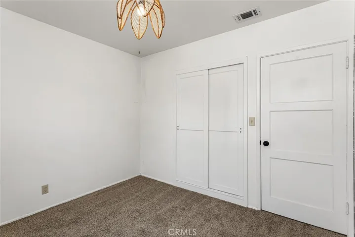 Front bedroom with sliding closet doors, vintage light fixture and new carpet.