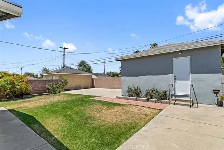 Backyard with garage, lawn and concrete slab for additional parking.