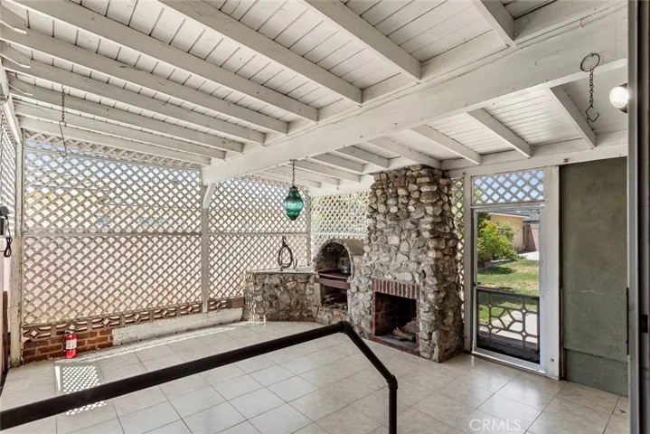 Lattice-enclosed covered patio with stone fireplace and wood-fired oven.