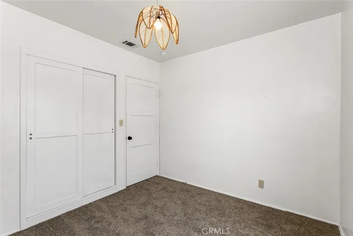 Front bedroom with sliding closet doors, vintage light fixture and new carpet.