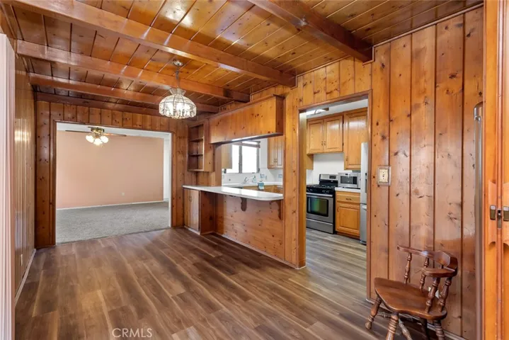 Wood paneled dining room with vintage Tiffany-style light fixture, breakfast bar and new wood-vinyl flooring.