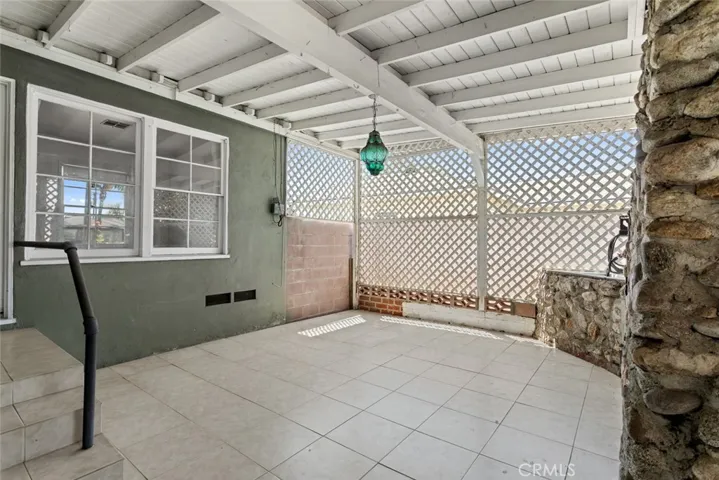 Lattice-enclosed covered patio with tile flooring.