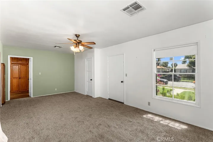 Living room with view of the neighborhood, new carpet and vintage ceiling fan.