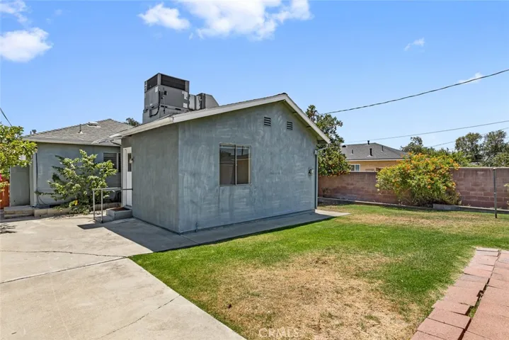 Backyard with lawn and side entrance to the house.