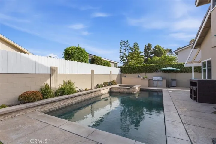 Private backyard featuring a sparkling pool and spa, expansive patio, built-in BBQ, grassy area, and multiple seating spaces, creating the perfect setting for outdoor entertaining and relaxation.