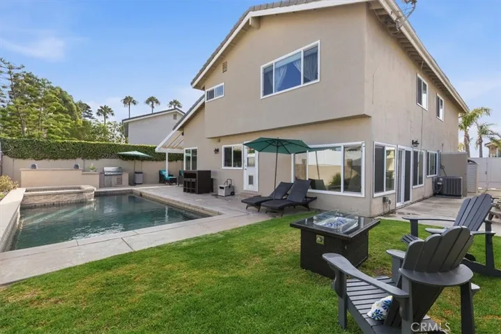 Private backyard featuring a sparkling pool and spa, expansive patio, built-in BBQ, grassy area, and multiple seating spaces, creating the perfect setting for outdoor entertaining and relaxation.