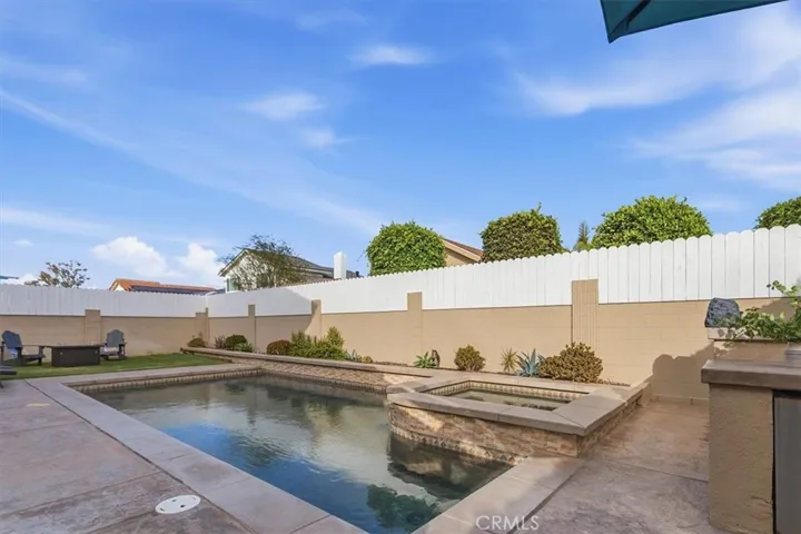 Private backyard featuring a sparkling pool and spa, expansive patio, built-in BBQ, grassy area, and multiple seating spaces, creating the perfect setting for outdoor entertaining and relaxation.