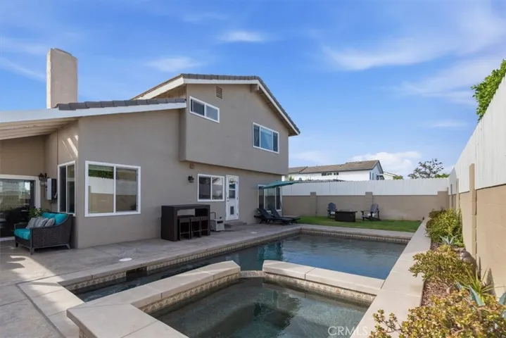 Private backyard featuring a sparkling pool and spa, expansive patio, built-in BBQ, grassy area, and multiple seating spaces, creating the perfect setting for outdoor entertaining and relaxation.