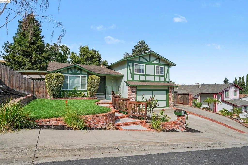 Tudor-style exterior with green trim and light siding, featuring a two-car garage