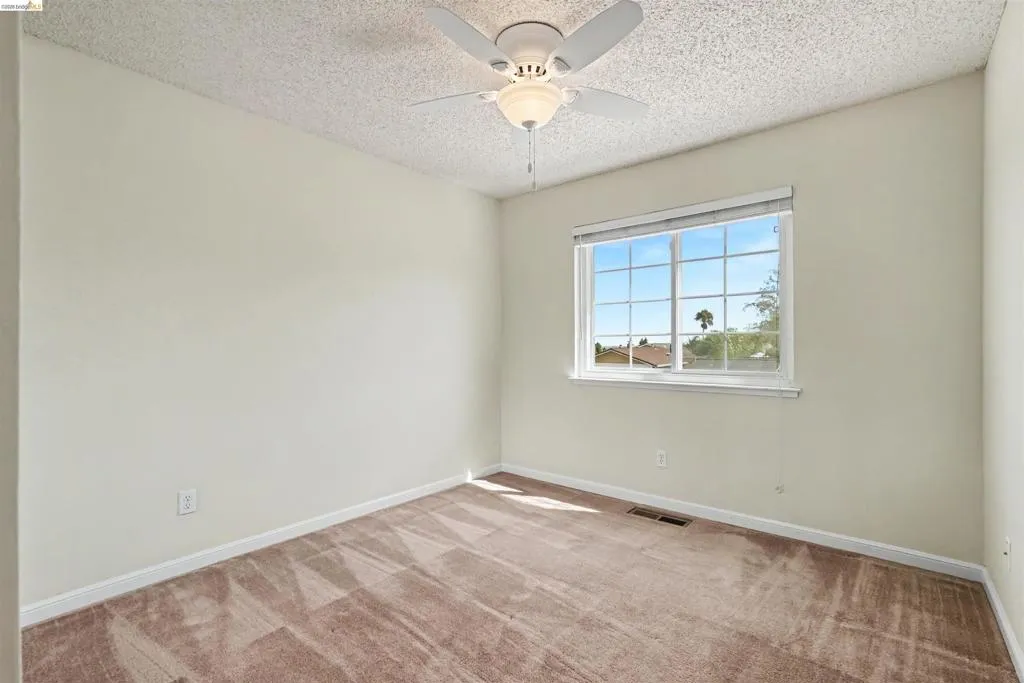Wall-to-wall carpeting, window with horizontal blinds, built-in ceiling fan with light fixture, and textured ceiling