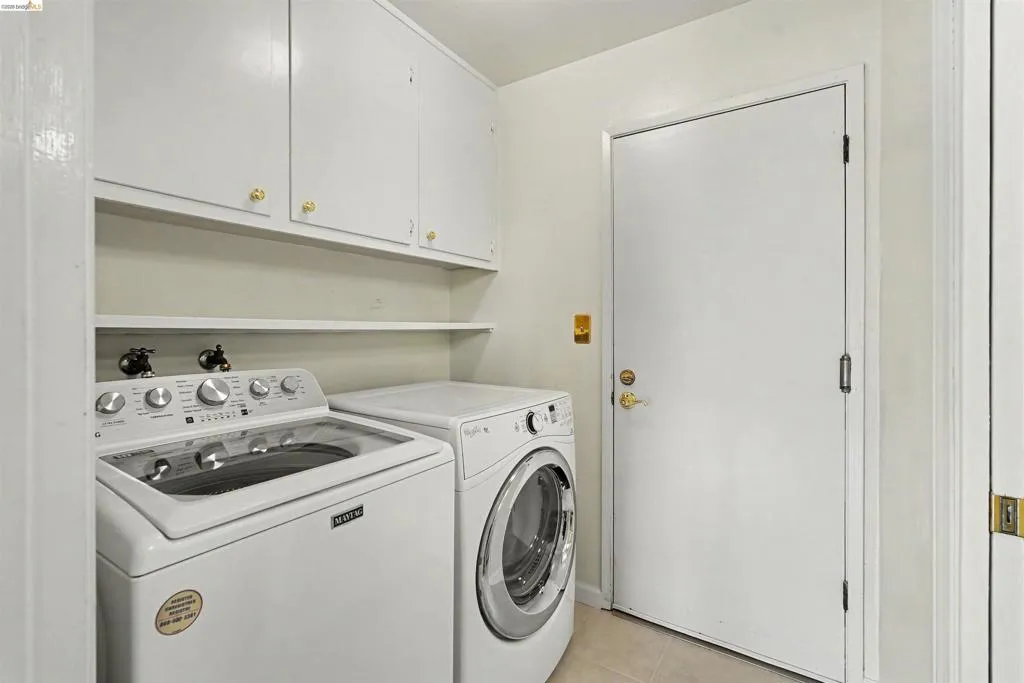 Laundry area with upper cabinetry and open shelving, featuring tile flooring