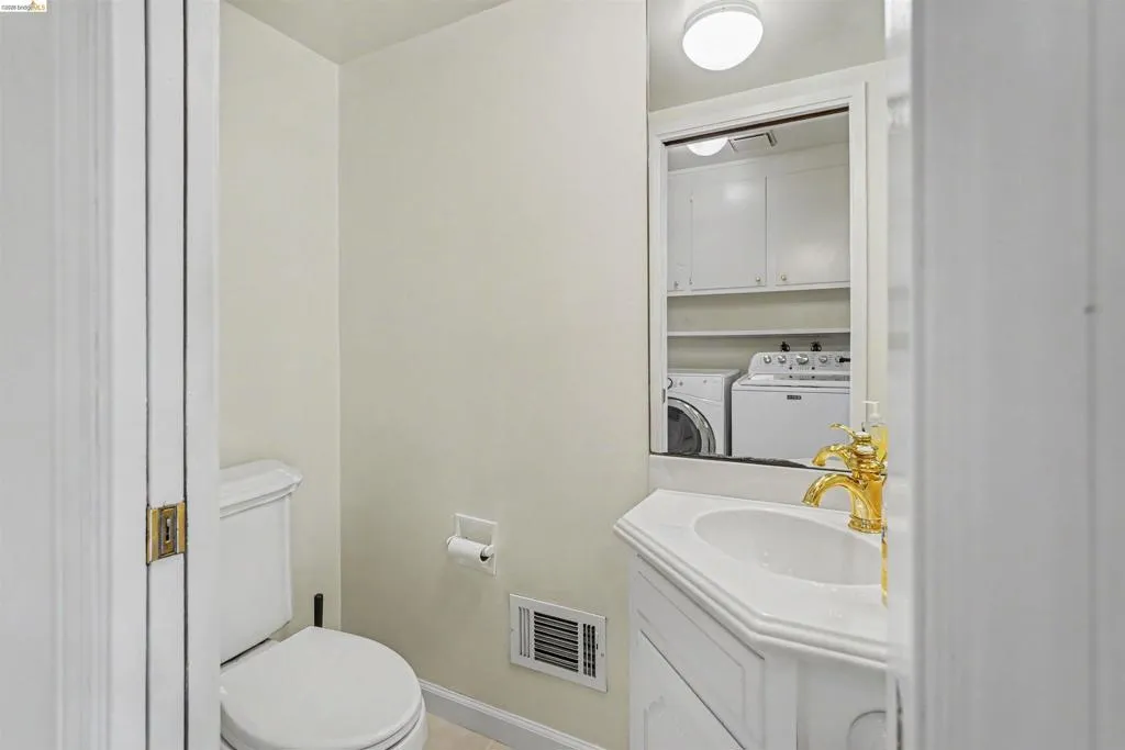 White vanity with an integrated sink, polished brass faucet, and a wall-mounted mirror