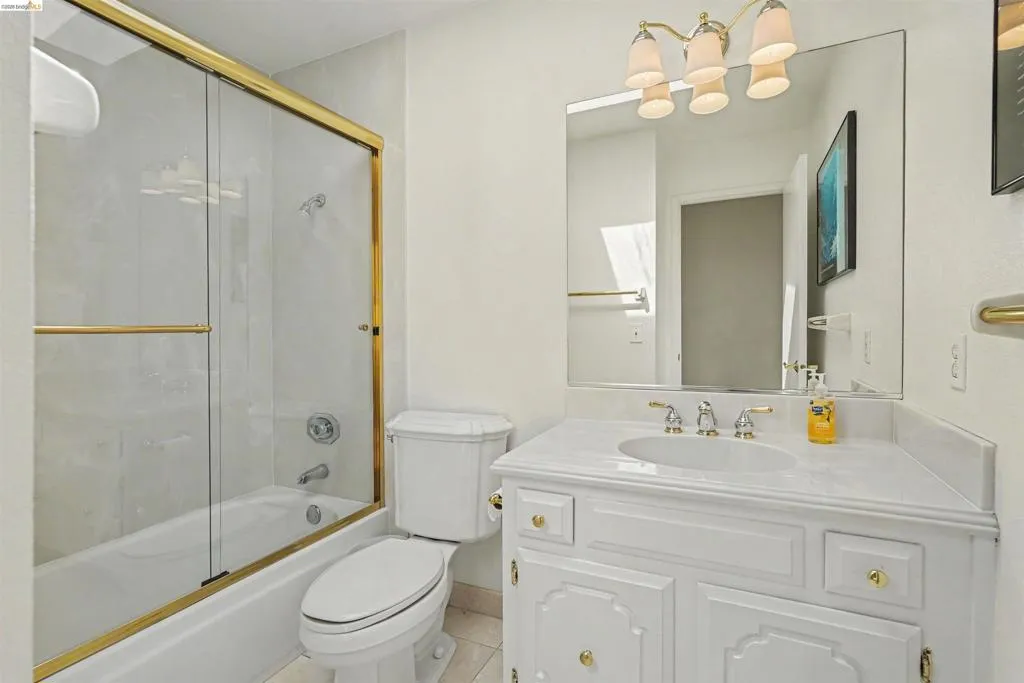 White vanity with gold-tone hardware, undermount sink, and a countertop