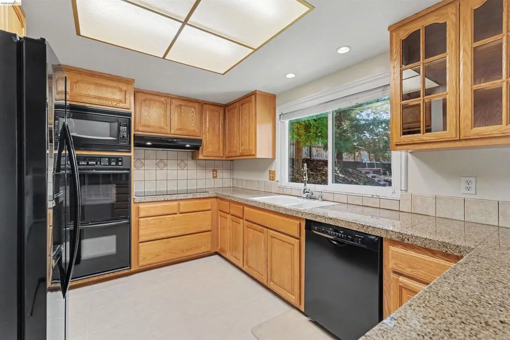Full kitchen with wood-finish cabinetry, granite-style countertops, and a tile backsplash