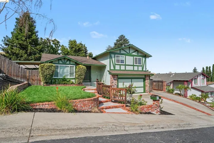 Tudor-style exterior with green trim and light siding, featuring a two-car garage