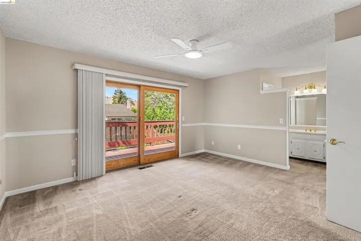 Carpeted flooring, ceiling fan, sliding glass doors, and an attached wood deck