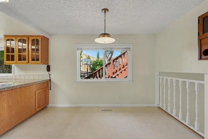 Kitchen area featuring wood cabinetry, tiled countertops, and a tile backsplash