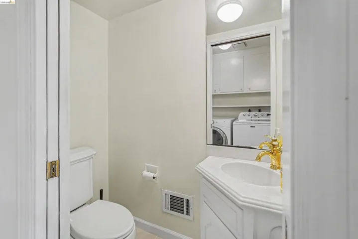 White vanity with an integrated sink, polished brass faucet, and a wall-mounted mirror