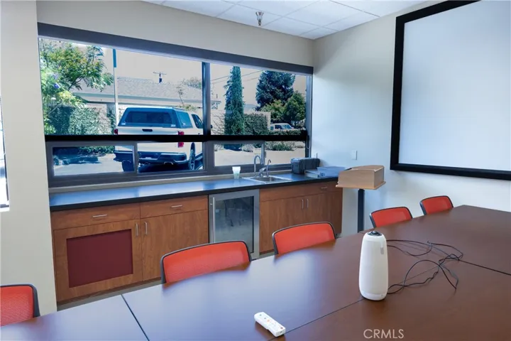The lower-level conference room features a convenient wet bar area with a sink and mini-fridge, all brightly lit by an abundance of natural light.