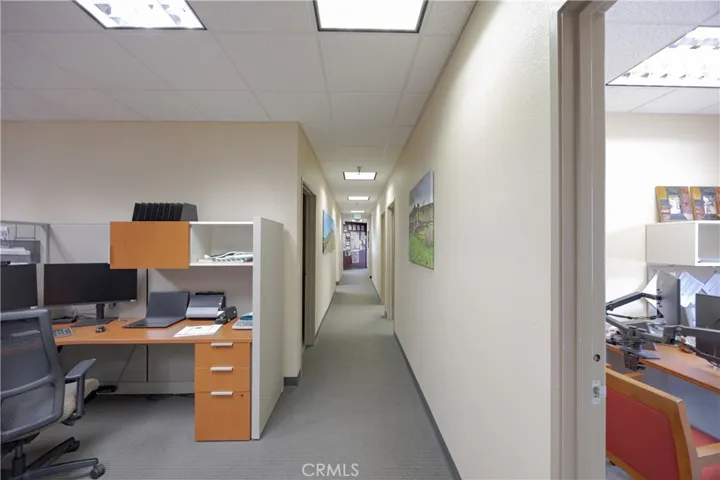 Easterly view of the building hallway looking toward the kitchen, featuring multiple offices on either side.