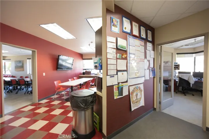 Split view showing a spacious conference room on the left, a kitchen and dining area in the center, and a corner office on the right.