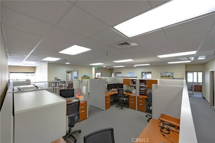 This spacious, well-lit upper-level cubicle office area is conveniently situated directly across from the main stairway landing, offering easy access and a professional workspace environment.