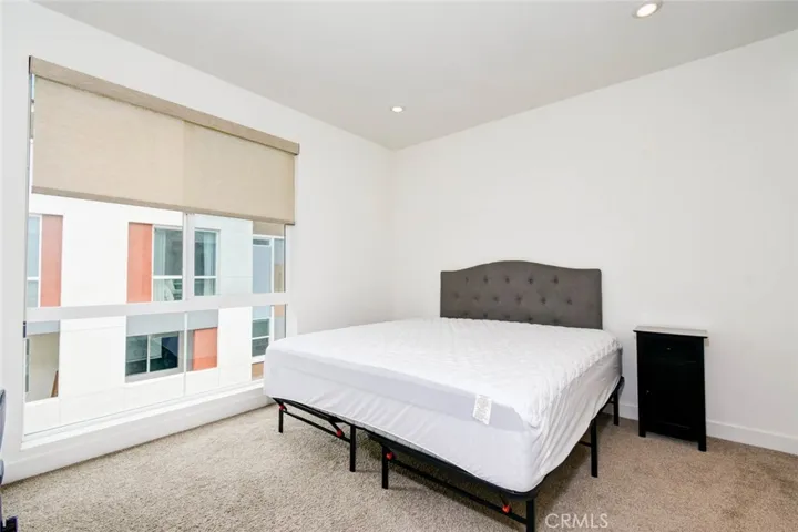 The primary bedroom on the thrid floor with carpeted floor and recess ceiling lights. Oversized window brings in plenty of lights.