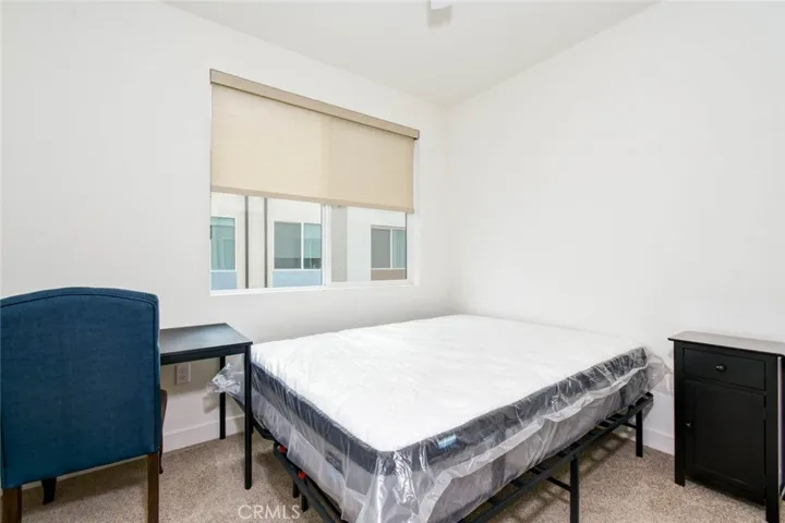 The third bedroom on the third floor is furnished with bed, desk and end table.