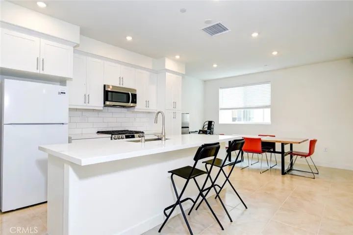 Kitchen island and the dining area are bright and clean space with tite flooring and recess ceiling lights. Plenty of cabinet and pantry space for storage.