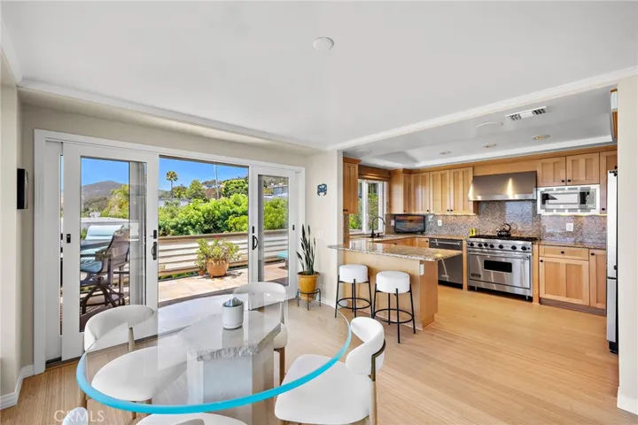 The kitchen features maple cabinetry, granite countertops, stainless steel appliances including a Viking oven with six-burner gas range, and opens seamlessly to the dining area and living room.