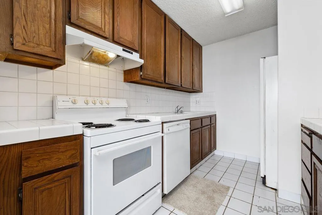 Standing in the hall looking into the kitchen with the stove, dishwasher, & sink. Look at all those spacious cabinets!!!