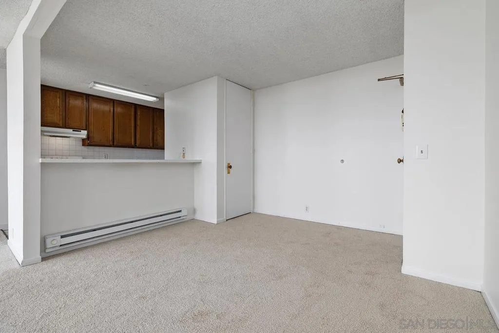 Looking across the living room with fresh paint and new carpet to the kitchen & entry area of the home. Bring a couple of tall bar stools for the counter looking into the kitchen.