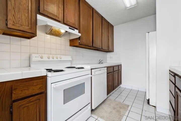 Standing in the hall looking into the kitchen with the stove, dishwasher, & sink. Look at all those spacious cabinets!!!