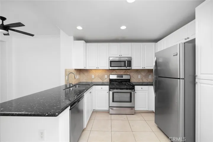 Thoughtfully designed kitchen features timeless white shaker cabinetry, low-maintenance quartz countertops, and stainless steel appliances.