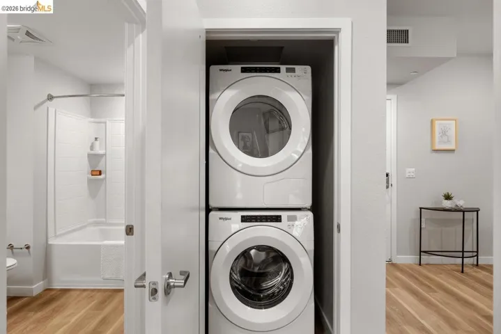 Washroom featuring light wood-type flooring and stacked washer and clothes dryer